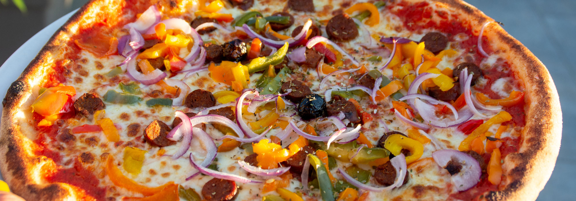 Pizza garnie de chorizo, poivrons et oignons rouges, sortie du four