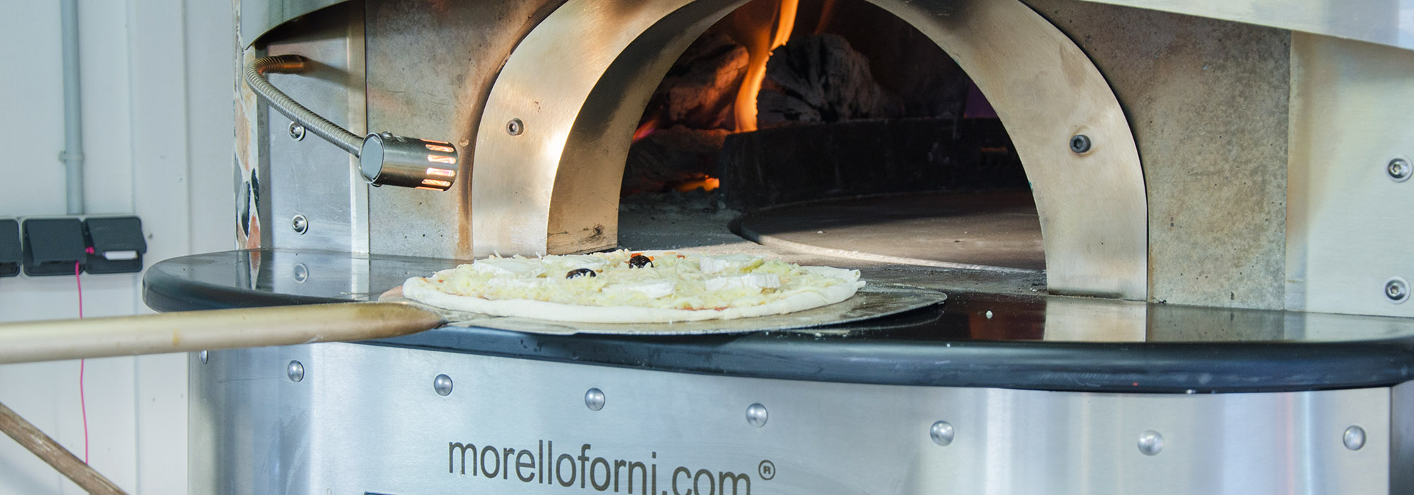 Pizza enfournée dans le four à bois